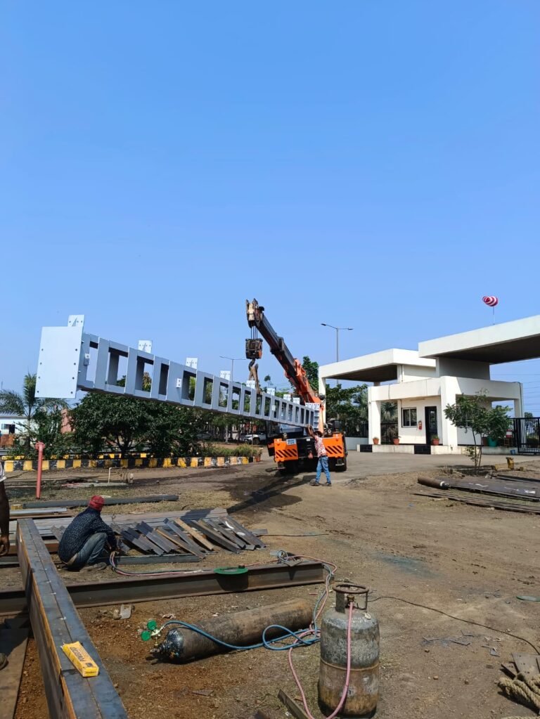 Crane lifting a fabricated steel girder while a welder works on site