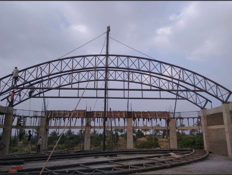 Arched steel roof truss being erected on site